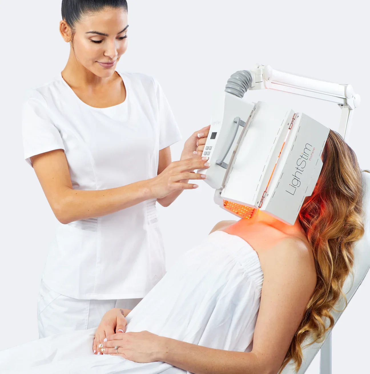 Esthetician using a LightStim ProPanel red light therapy device on a client in a spa setting. Professional-grade LED light therapy panel delivers FDA-cleared anti-aging, wrinkle reduction and skin rejuvenation benefits.